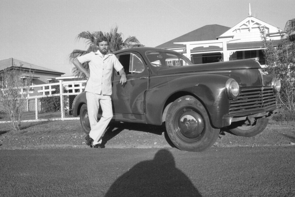 Man standing outside timber house with Peugeot 203 car, Ipswich, February 1978
