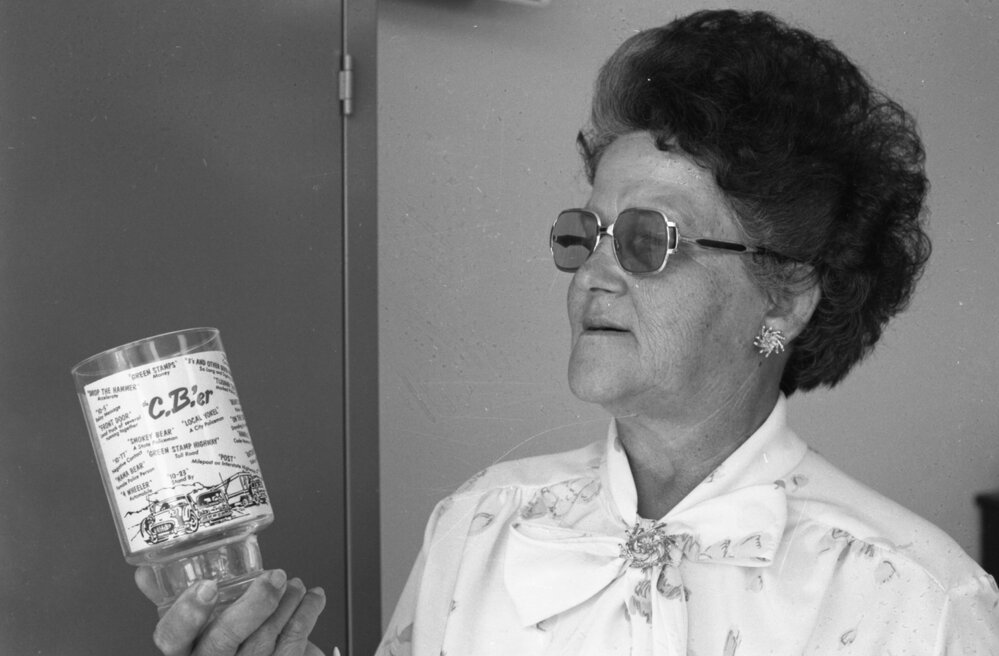 Vera Vieth holding a C.B.'er glass covered in trucker jargon, Ipswich, October 1977
