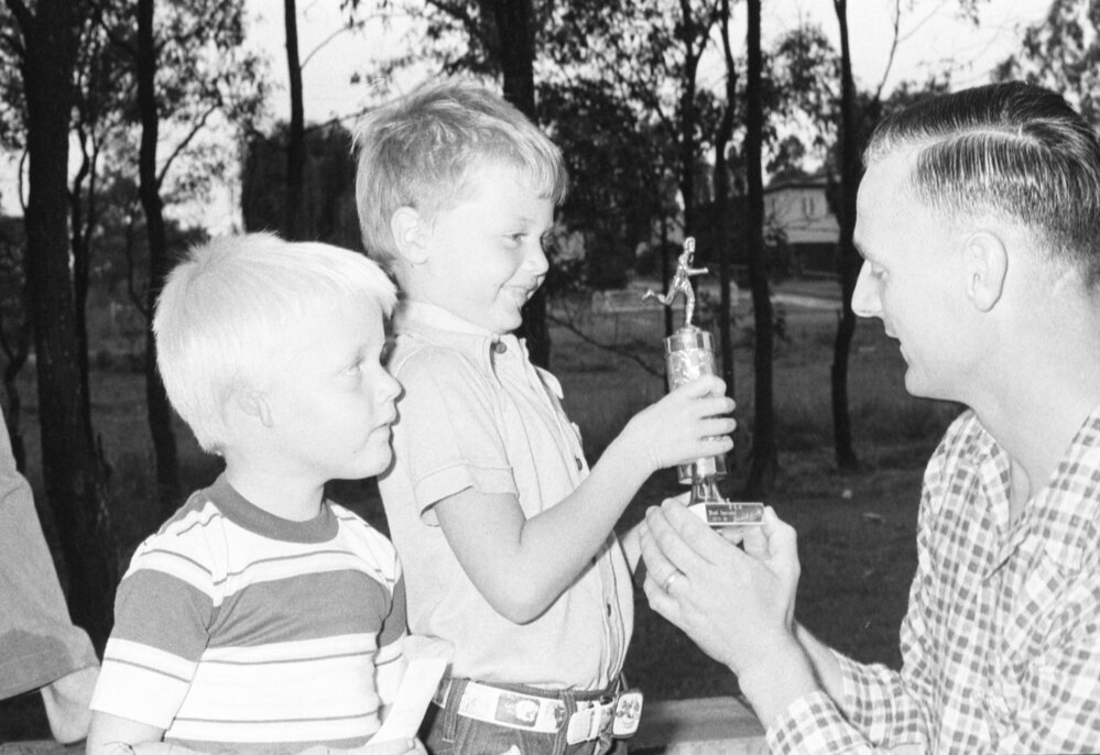 Daniel Hull receiving Little Athletics trophy from unidentified man with unidentified boy, Ipswich, Queensland