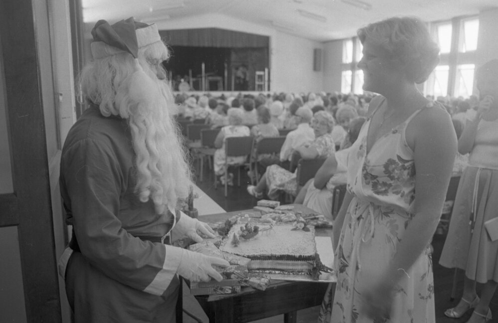 Special guest Santa with Christmas cake at a Christmas Concert thought to be at St Paul's Church Hall, Ipswich, Queensland, December 1979