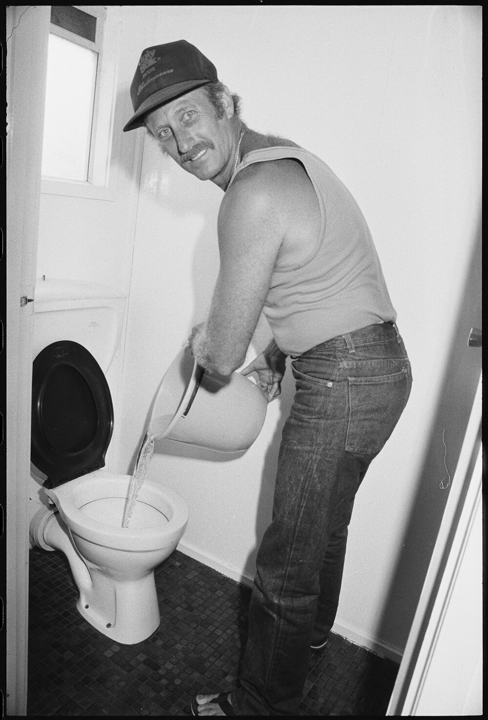 Unidentified man pouring liquid into the toilet, Ipswich, January 1986 