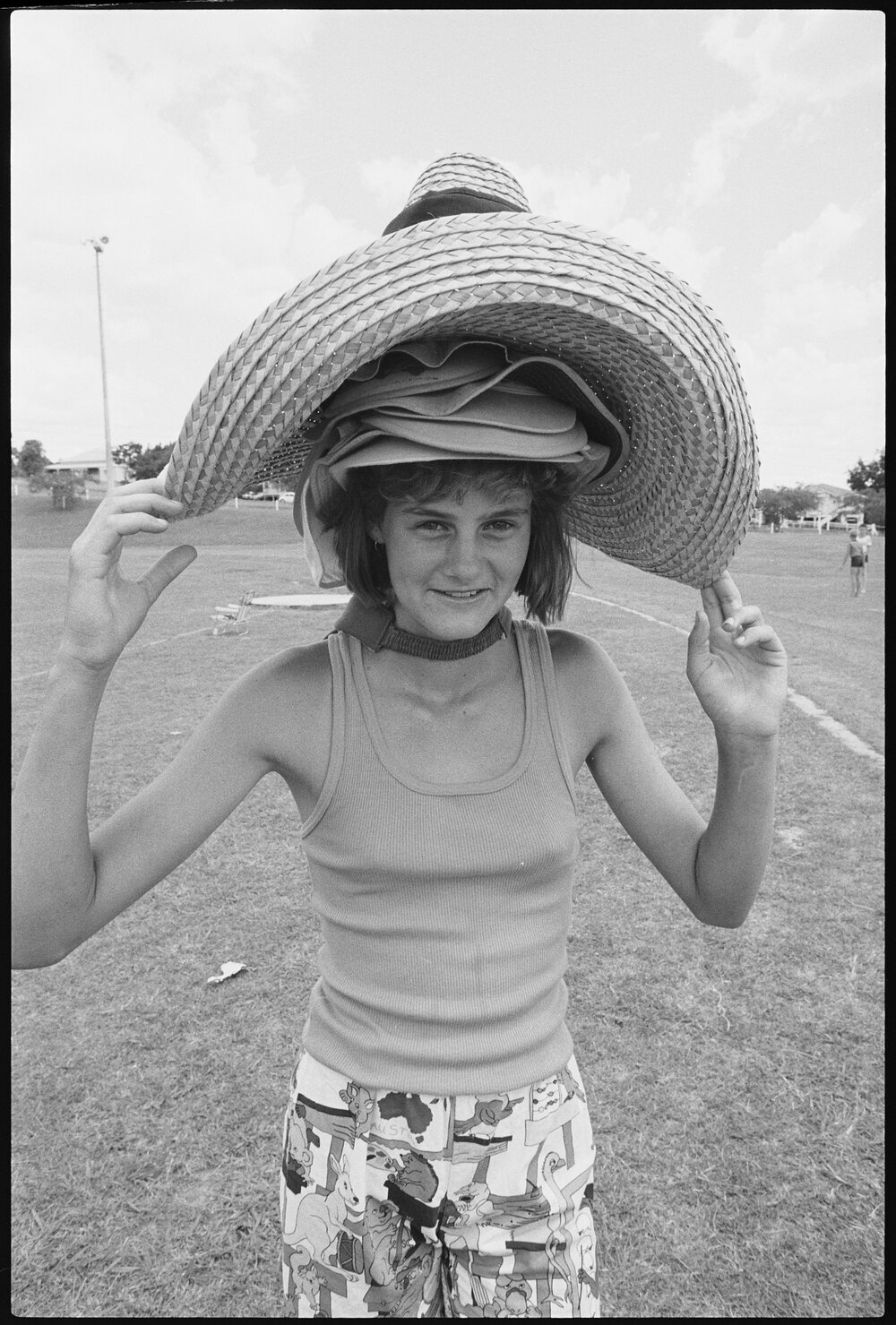Unidentified young woman wearing a stack of multiple hats at a sports field, Ipswich, January 1986