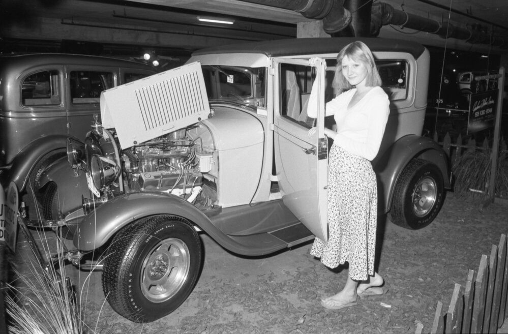 Unidentified woman standing beside a vintage 1928 Ford Sedan car at a Hot Rod Show, Ipswich, August 1980