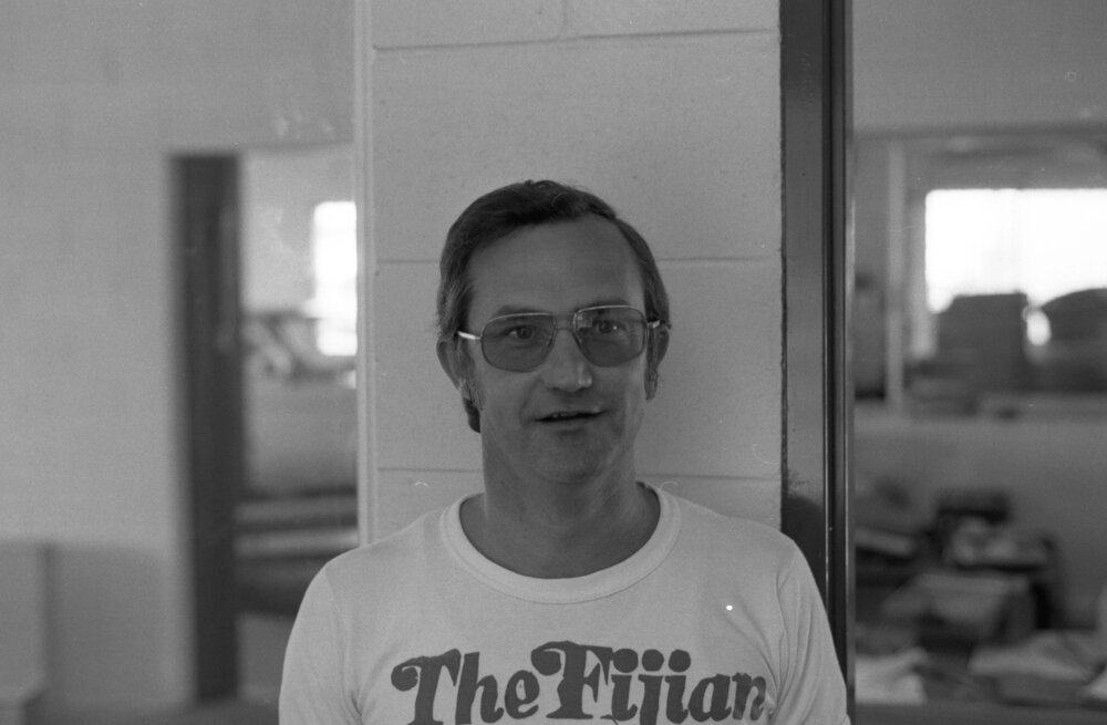 Employee at Jeff Denman's Tyre &amp; Auto Service wearing a 'The Fijian' shirt, Ipswich, August 1980