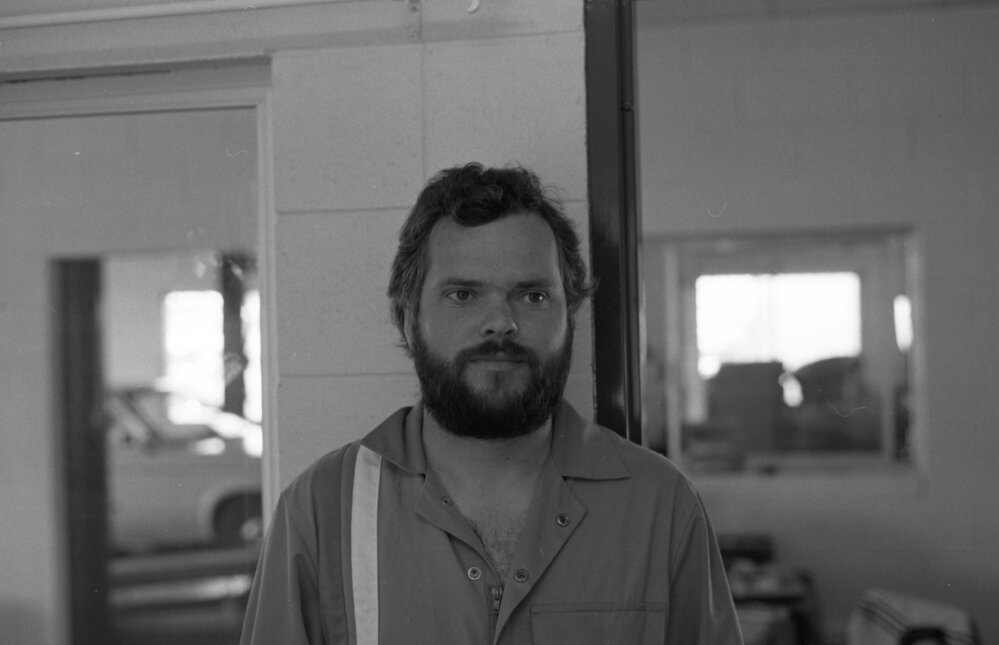 Bearded employee at Jeff Denman's Tyre &amp; Auto Service, Ipswich, August 1980