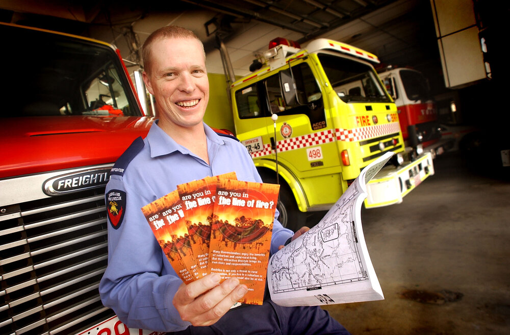 Tim Morris holding bush fire news pamphlets, Ipswich, December 2003