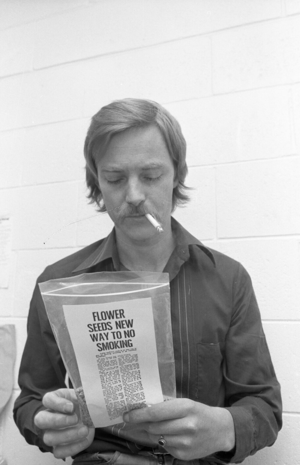 Unidentified man smoking with sunflower seed packet encouraging quitting smoking, Ipswich, September 1980