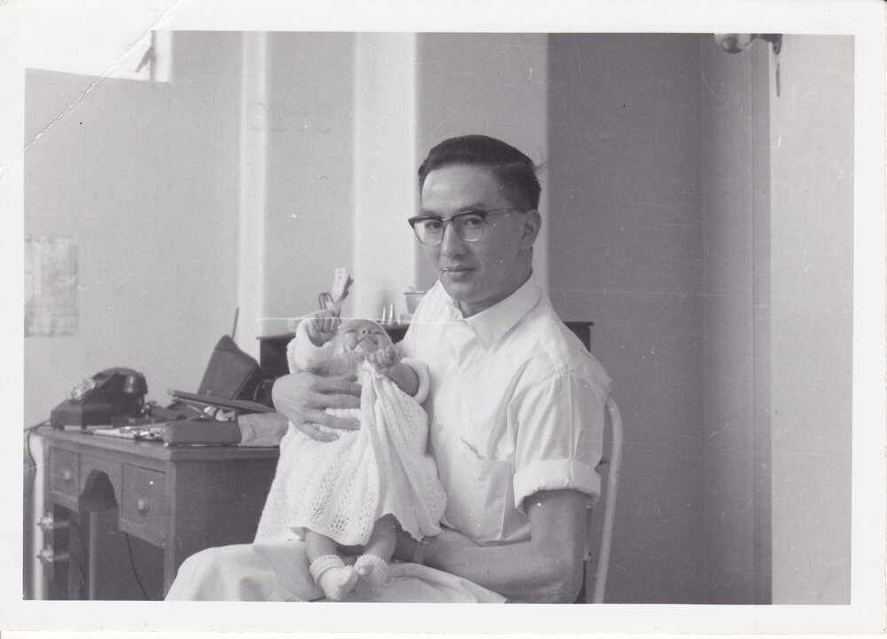 Doctor Chiu holding unidentified baby in office, Ipswich Hospital, Ipswich, 1950s