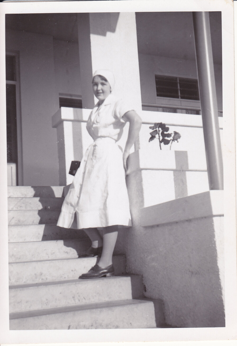 Nurse Gloria Young (nee Batzloff) standing at the steps of Trumpy House, Ipswich General Hospital, Ipswich, 1950s
