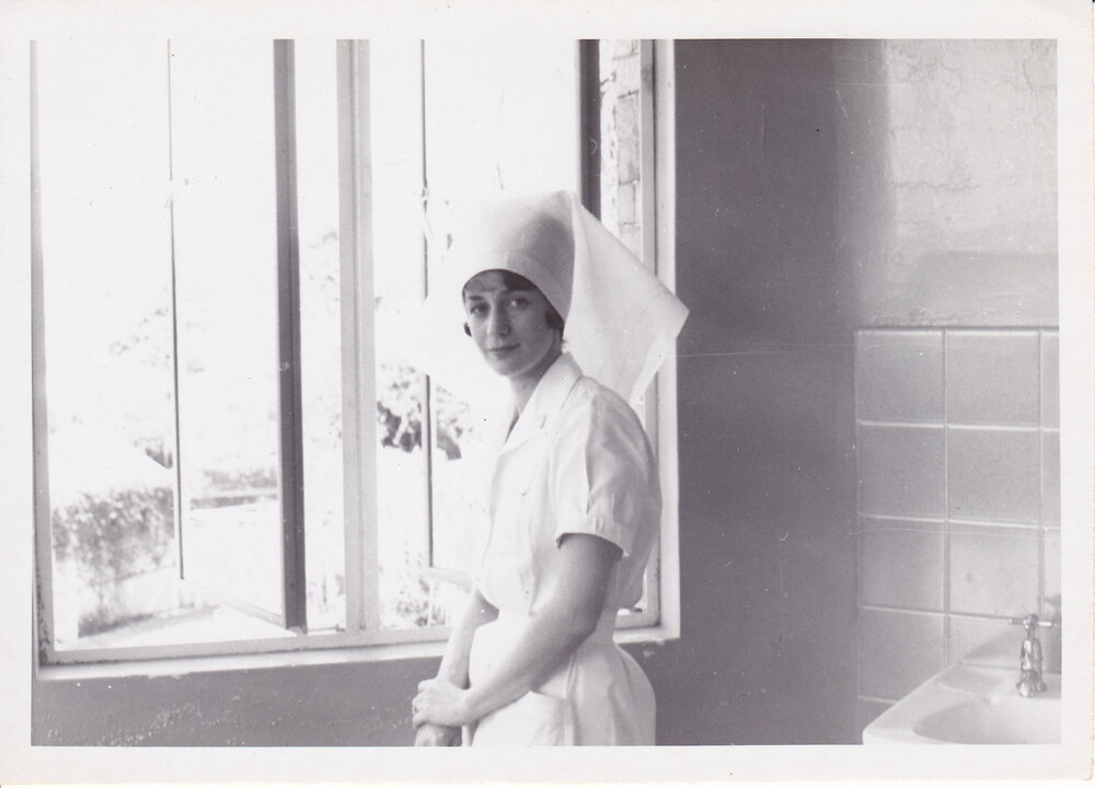 Sister Bernadette Smith (Tracey) at window by hand basin, 1950s