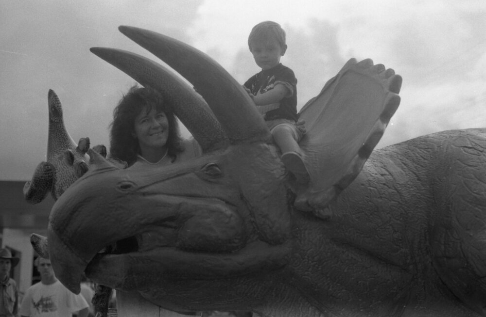 Young boy riding a triceratops with unidentified woman with inflatable stegosaurus during the theatrical release of Jurassic Park, Brisbane, August 1993
