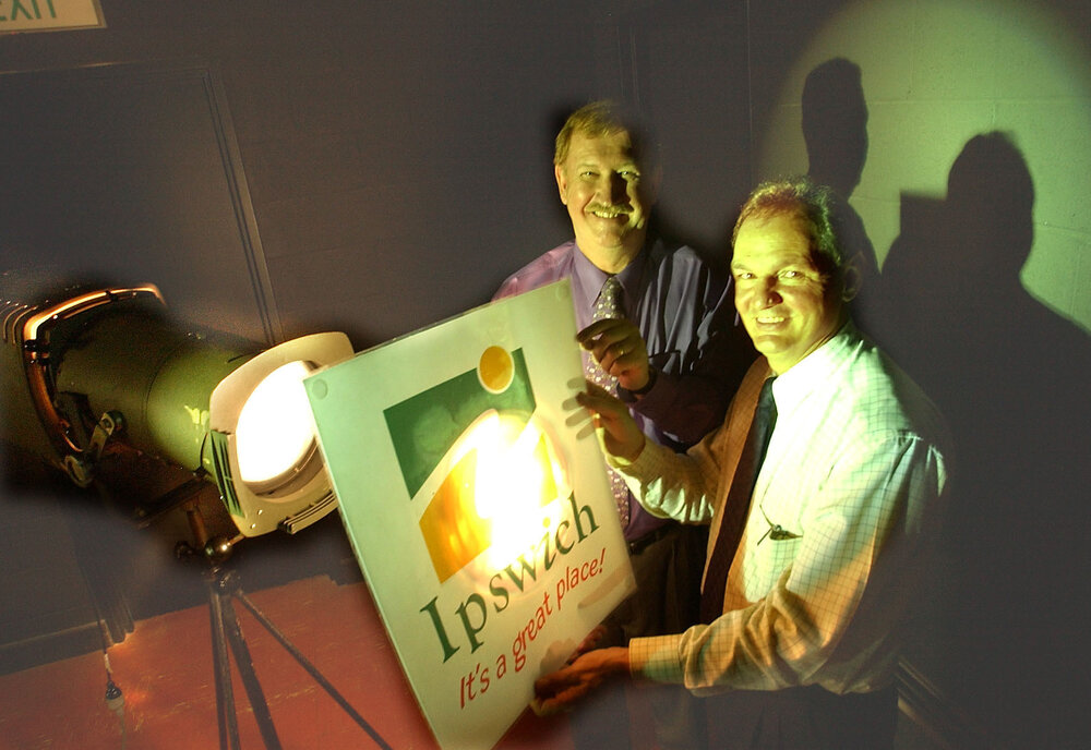 Arthur Frame and Mayor Paul Pisasale holding a City of Ipswich sign in front of a spotlight, Ipswich, February 2003