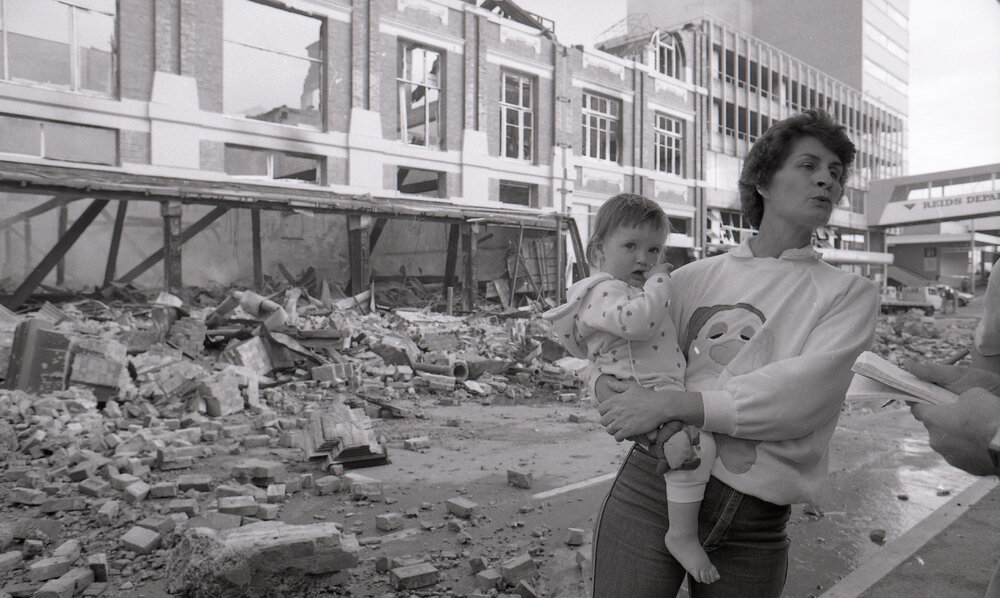 Mother and child view the aftermath of the Reid's (Cribb &amp; Foote) fire, Bell Street, Ipswich, August 1985