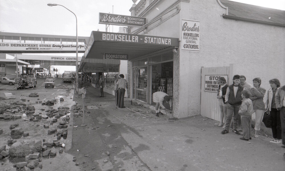 Crowd gathered outside of Brodies bookstore viewing the aftermath of the Reid's (Cribb &amp; Foote) fire, Bell Street, Ipswich, August 1985