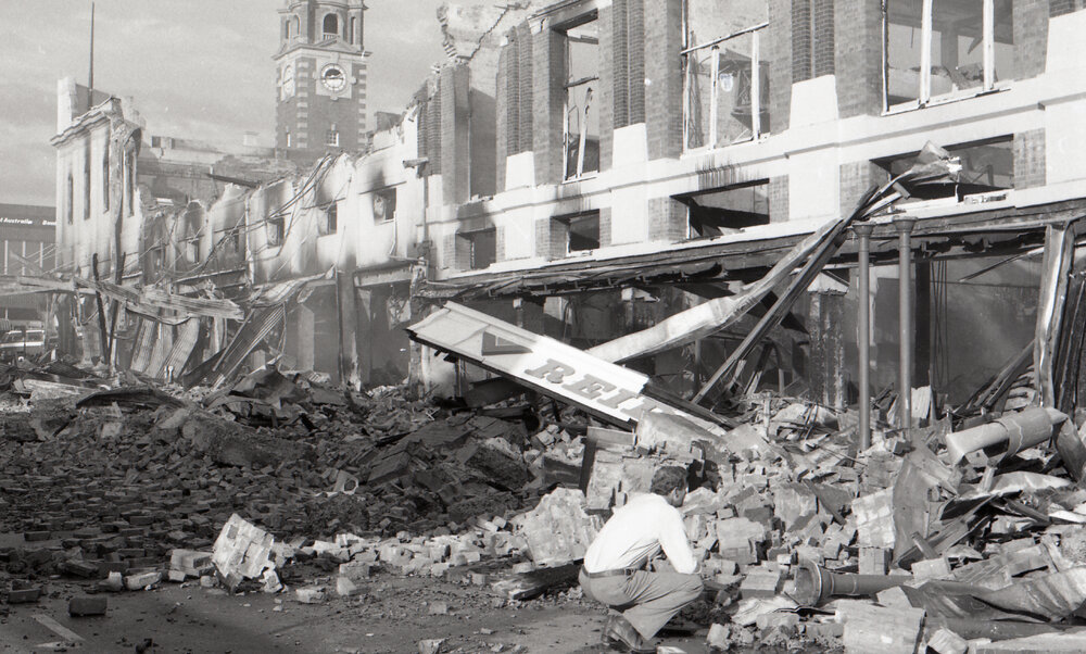 Man inspecting the aftermath of the Reid's (Cribb &amp; Foote) fire, Bell Street, Ipswich, August 1985