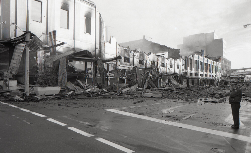 Police officer inspecting the aftermath of the Reid's (Cribb &amp; Foote) fire, Bell Street, Ipswich, August 1985