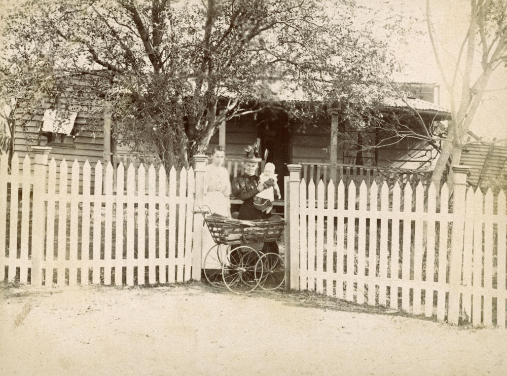Two women with a child and pram in front of house, Ipswich, early 1900s