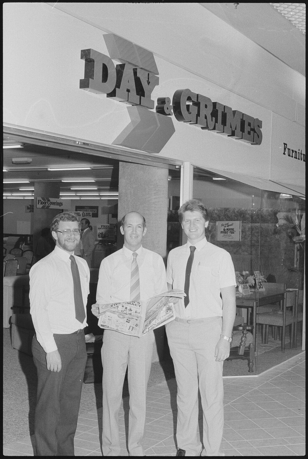 Unidentified men in front of Redbank Plaza Shopping Centre Day &amp; Grimes Furniture store during grand opening, Redbank, September 1985