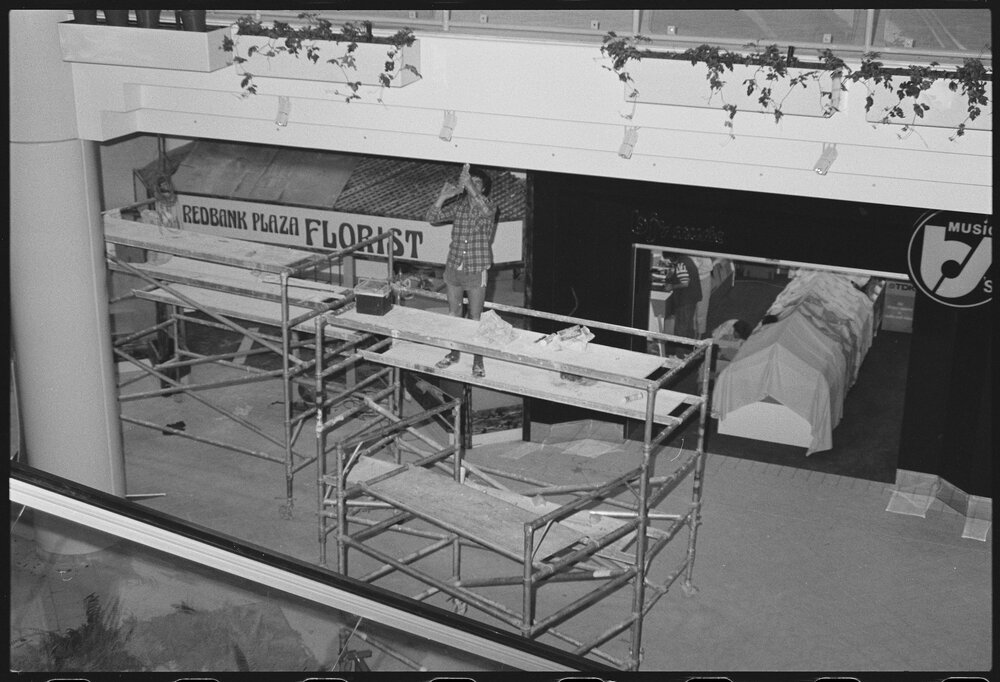 Unidentified workman outside Redbank Plaza Florist in Redbank Plaza Shopping Centre during construction, Redbank, September 1985