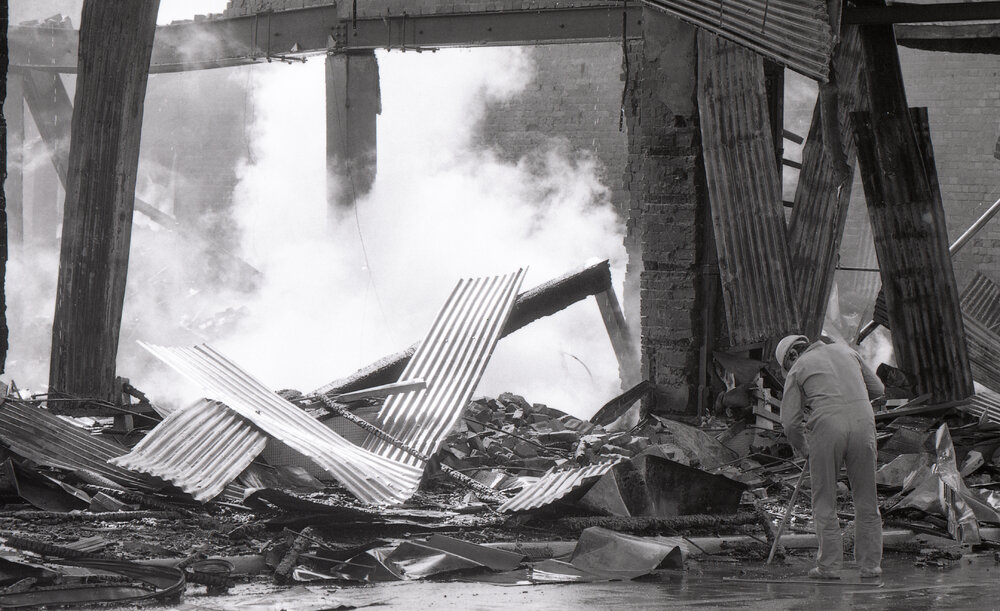 Man inspecting the aftermath of the Reid's (Cribb &amp; Foote) fire, Bell Street, Ipswich, August 1985