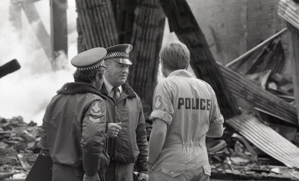 Police officers inspecting the aftermath of the Reid's (Cribb &amp; Foote) fire, Bell Street, Ipswich, August 1985
