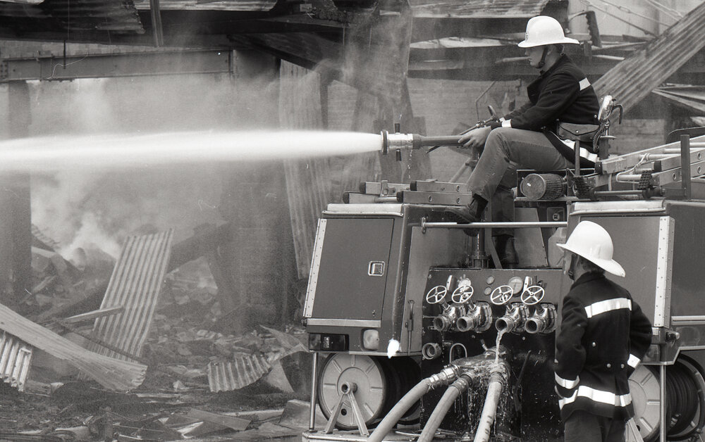 Firefighters hosing down the remains of the Reid's store following the fire, Ipswich, August 1985