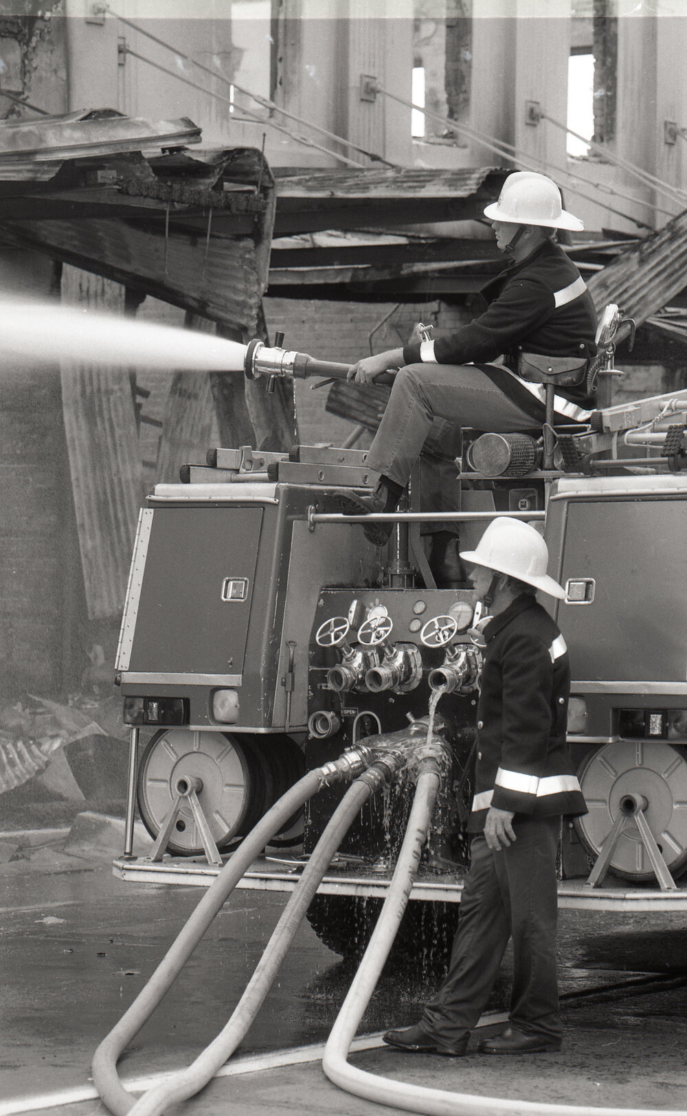 Firefighters hosing down the remains of the Reid's store following the fire, Ipswich, August 1985