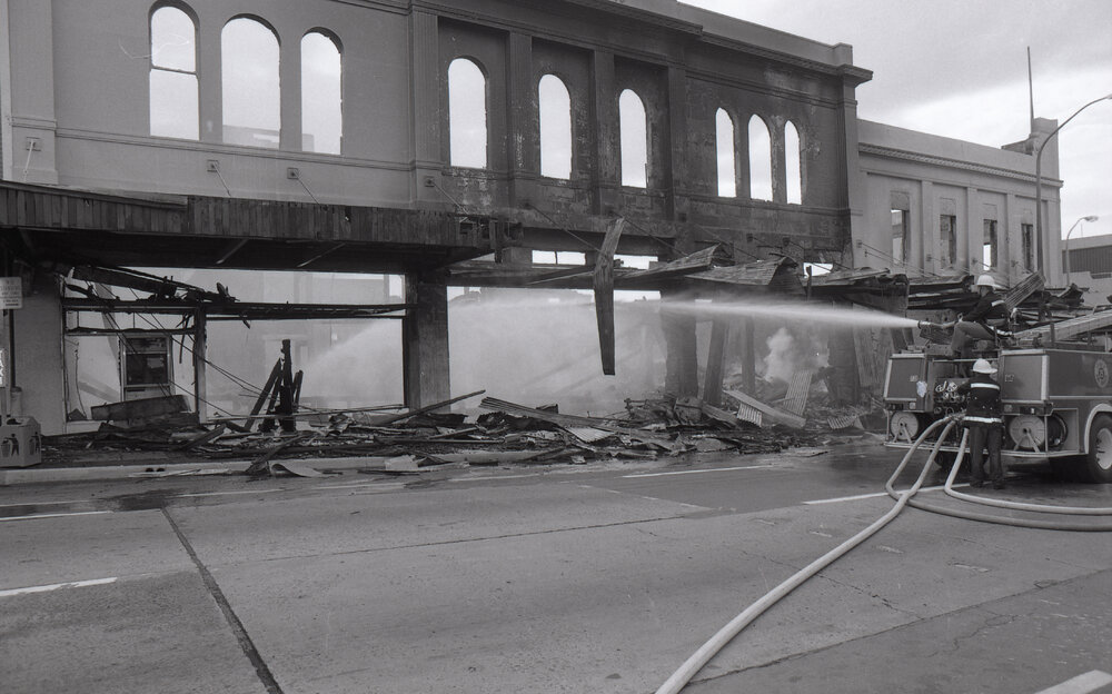 Firefighters hosing down the remains of the Reid's store following the fire, Ipswich, August 1985