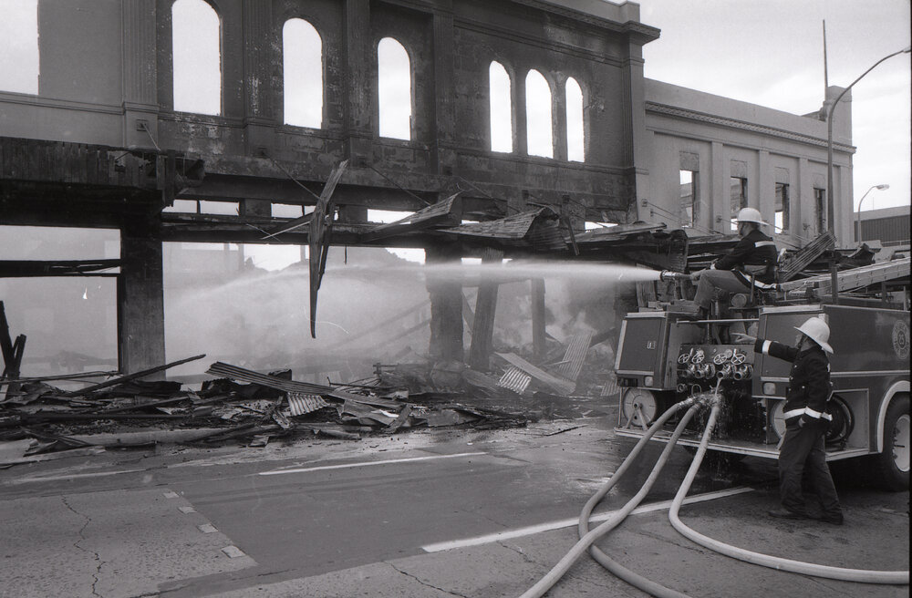 Firefighters hosing down the remains of the Reid's store following the fire, Ipswich, August 1985