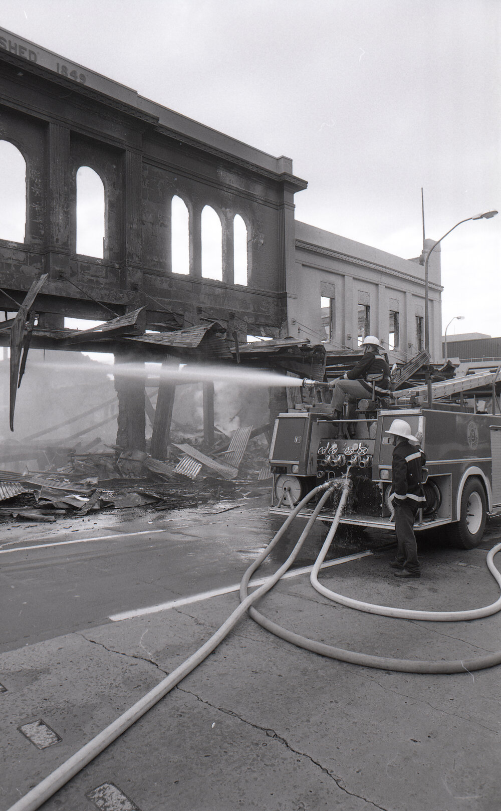 Firefighters hosing down the remains of the Reid's store following the fire, Ipswich, August 1985