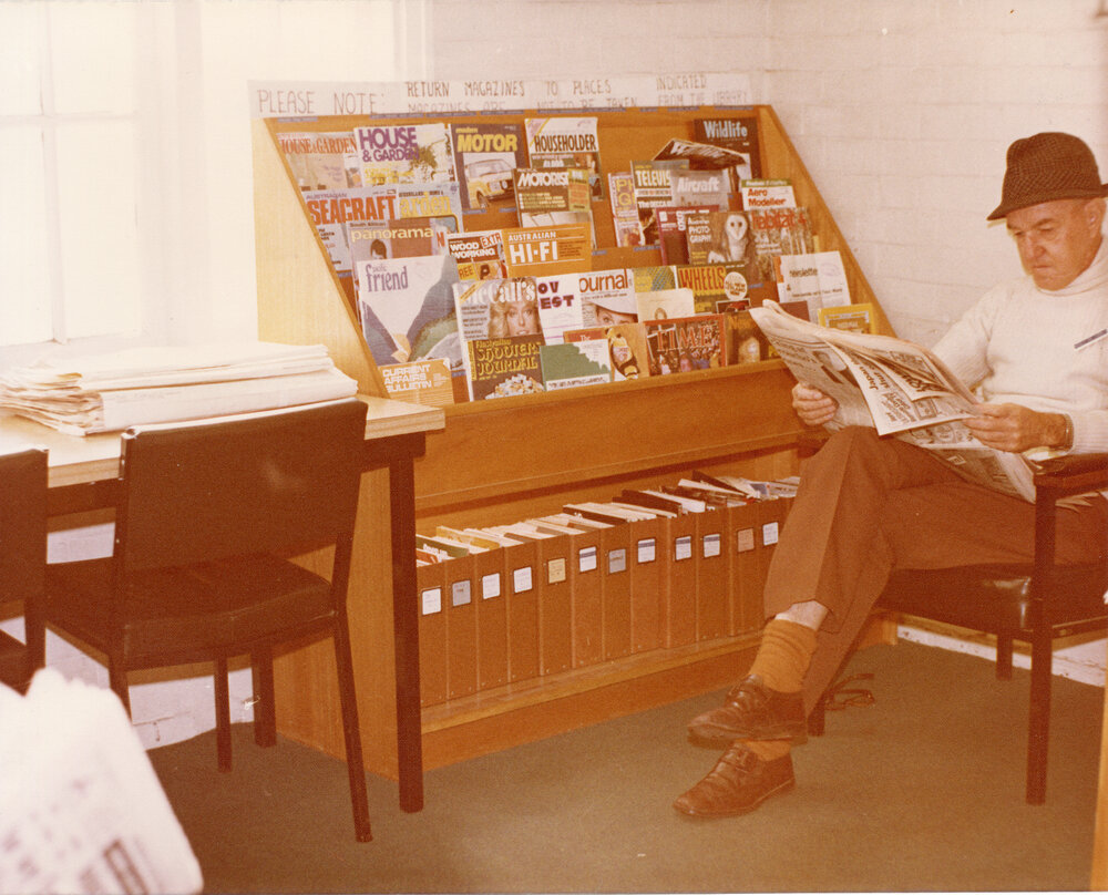 Library customer Mr Sneyd, reading the paper next to the magazine stand, Ipswich Municipal Library, corner of Nicholas and Limestone Streets, Ipswich, 1970s