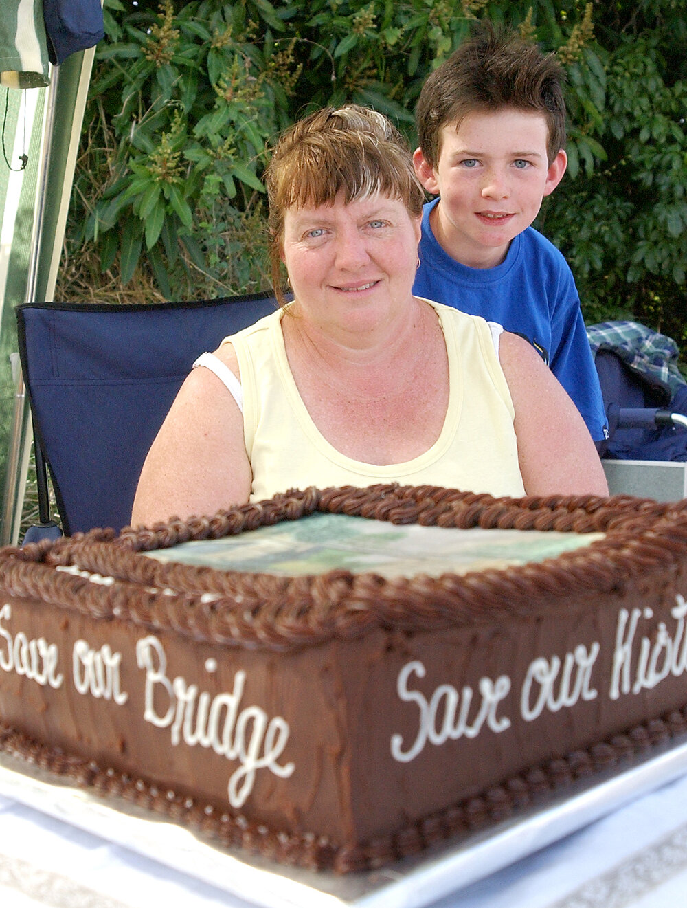 Deanna and Jared McDonald (aged 8) at the Heiner Road bridge with the caked baked by Deanna, Ipswich, September 2004 