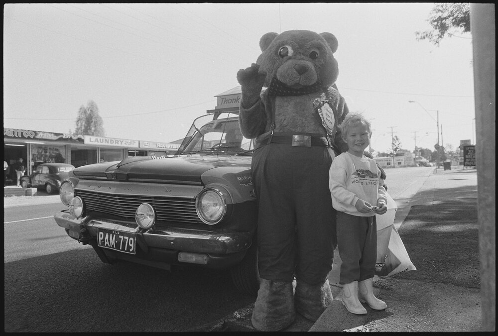 Unidentified child with the L.J. Hooker real-estate bear mascot and car entered in the Variety Bash, location unknown, 4th August 1994