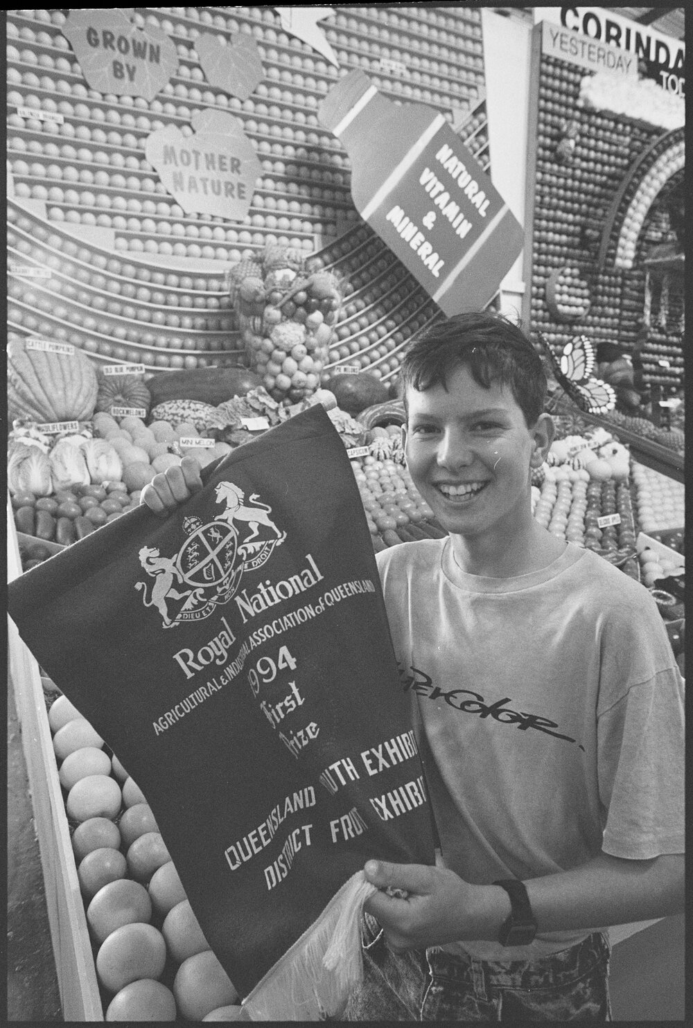 Unidentified boy with First Prize banner in front of the Kalbar fruit display at the Ekka, Brisbane Showgrounds, Brisbane, 18th August 1994