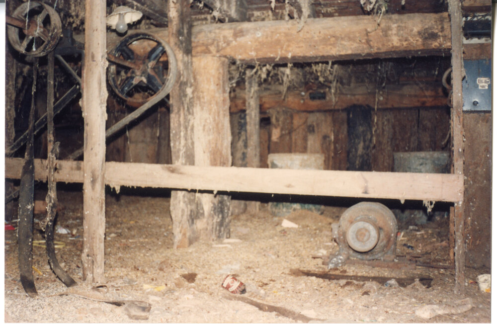 Hand hewn logs and old machine belt pulleys in the cellar of Risson's Produce