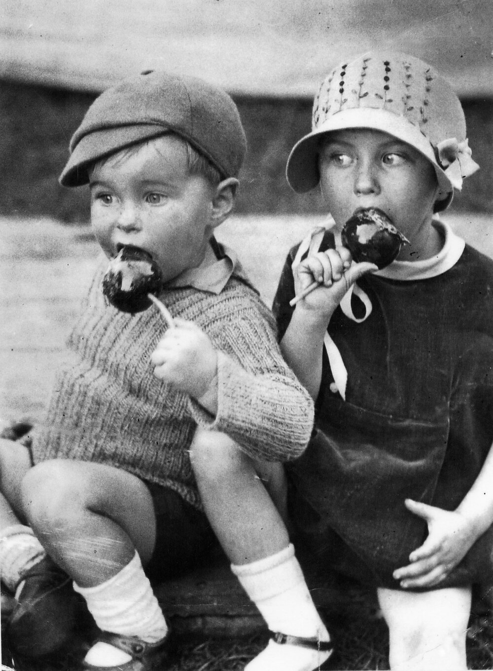 Ken Booth, 2, with sister Wray Duncanson, 4, (nee booth) eating toffee apples at the Ipswich Show, Ipswich, 1934