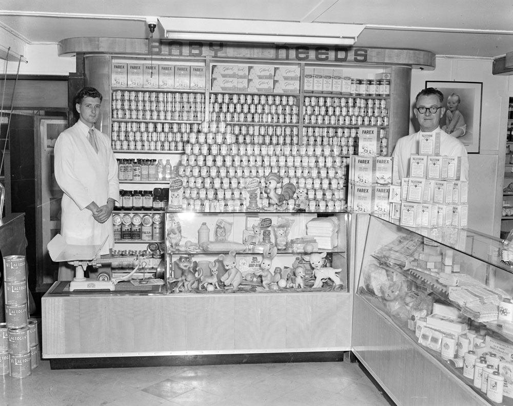 Staff with Nolans Pharmacy Baby Products display, corner of Brisbane and Nicholas Streets, Ipswich, 1955