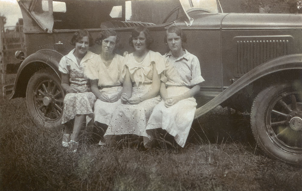 Four unidentified women sitting on running board of car, Booval, Ipswich, 1920s