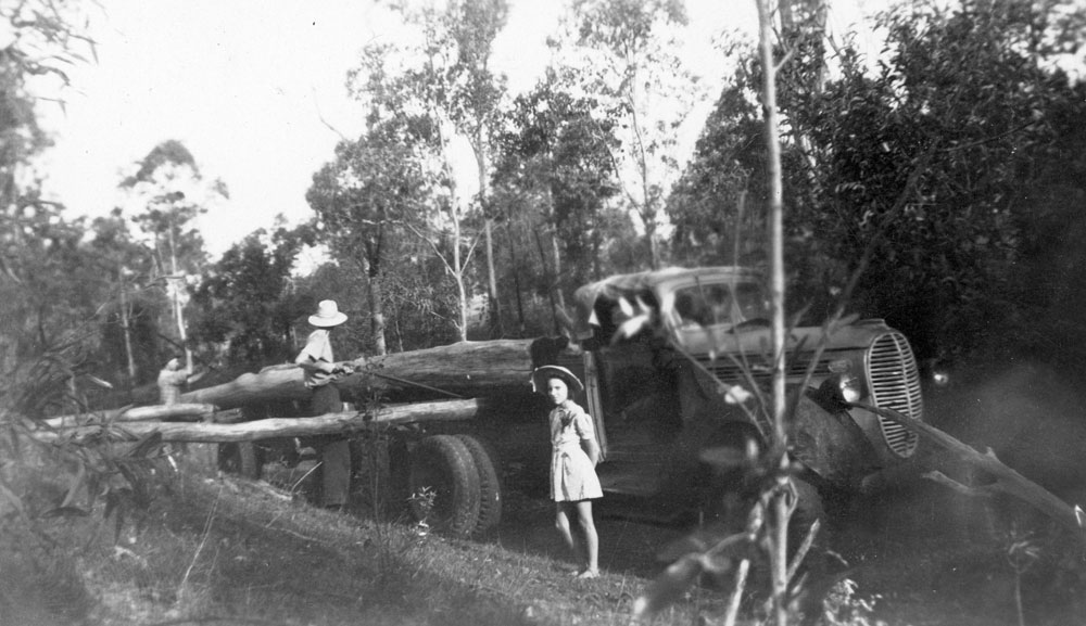 Two men loading logs on truck on farm at Ironpot Creek, Blacksoil, Ipswich, 1948