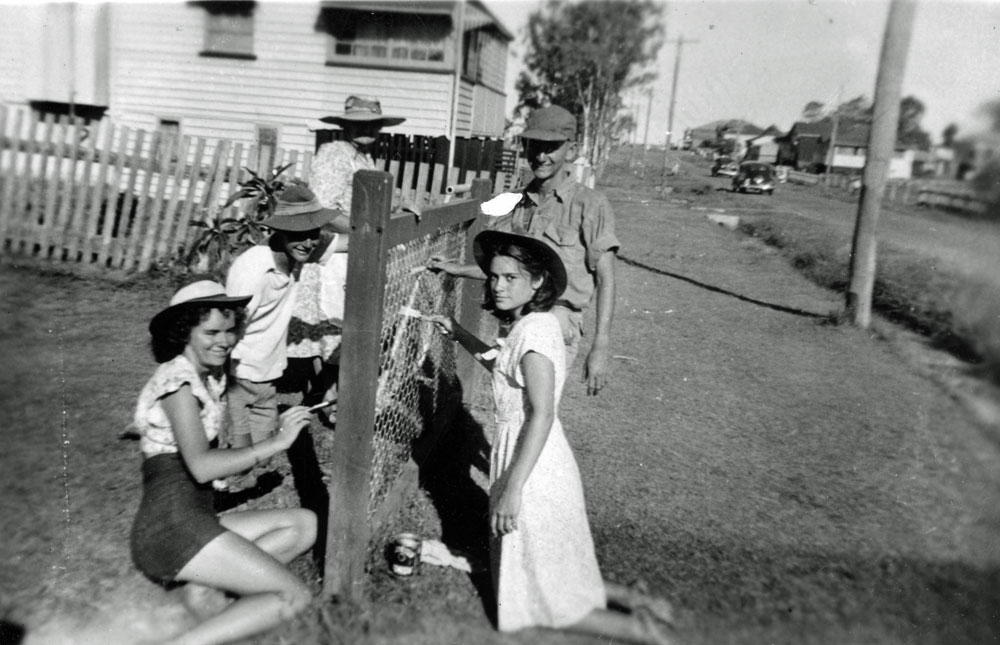 Family painting a fence in East Ipswich, 1948-1949