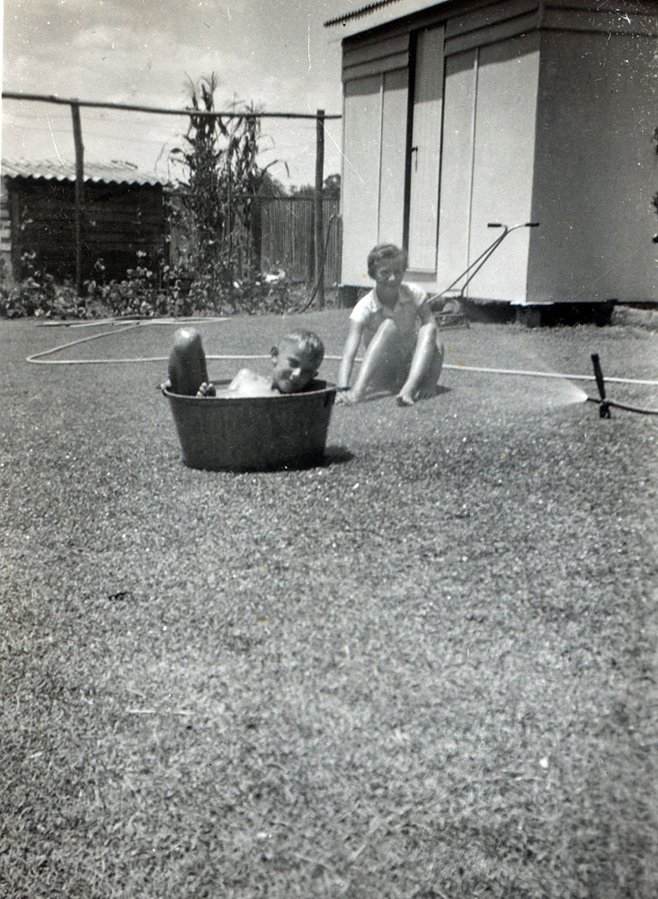 Children playing with hose and galvanised washing tub, backyard Alice Street, Blackstone early 1950s