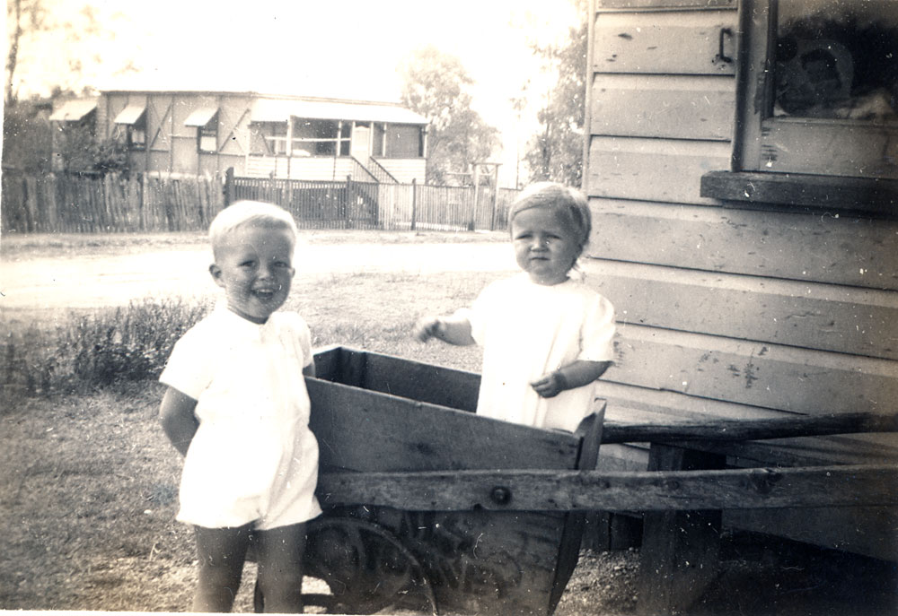 Children playing in cart under shop awning of the Trevis Brothers store at 1 Alice Street, Blackstone, Ipswich, 1942