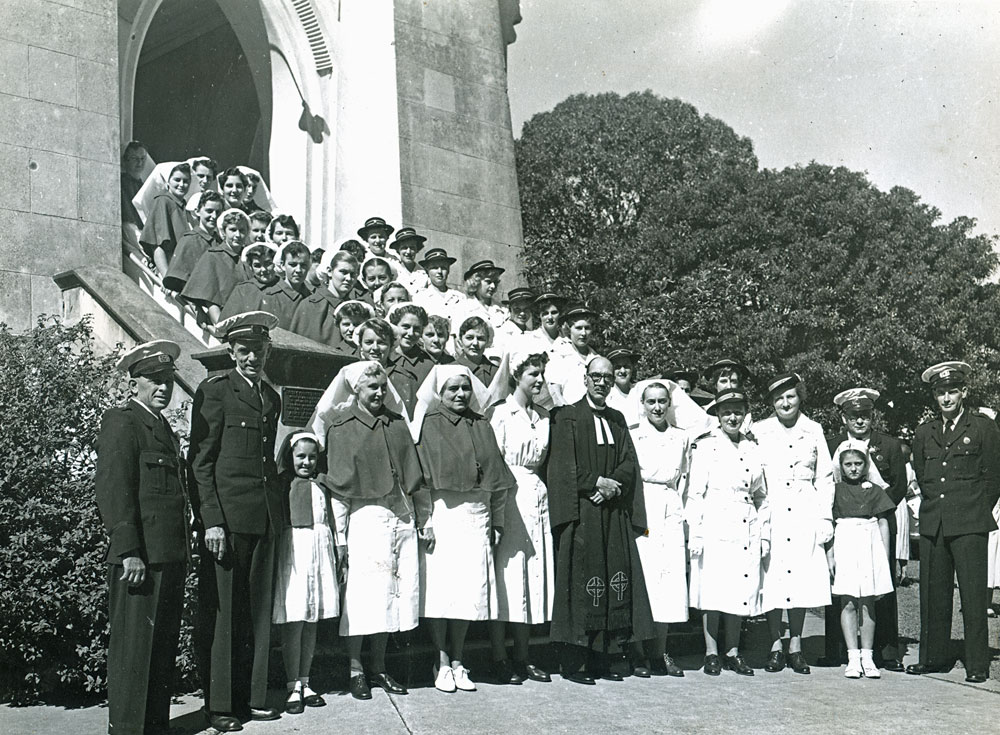 Heather Kennedy and Betty Pedersen grouped with  nurses and ambulance officers on the stairs of St Stephen's Presbyterian Church following Sunday church services, Ipswich, 10 May 1953