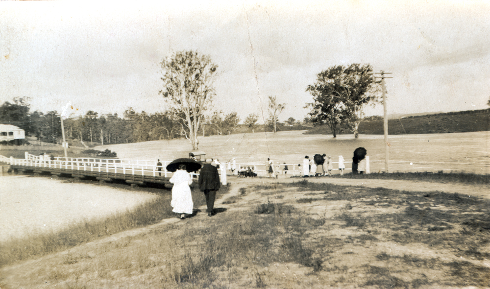 Group of people viewing flooded bridge from Delacy Street to Tantivy, North Ipswich, 1920s