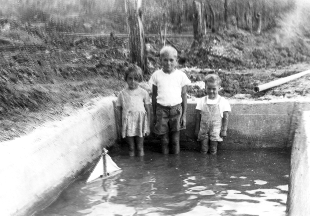 Arthur Kathage's family playing with boat in silt trap, Westfalen Mine No. 2, Dinmore, Ipswich, 1950