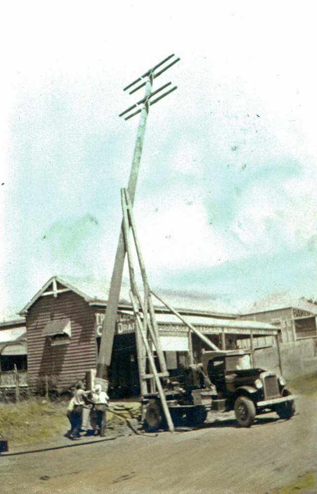Erecting a power pole in front of Proudlock's store at Marburg, Ipswich, early 1920s