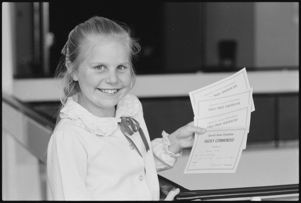Debra King holding award certificates, Ipswich, July 1985