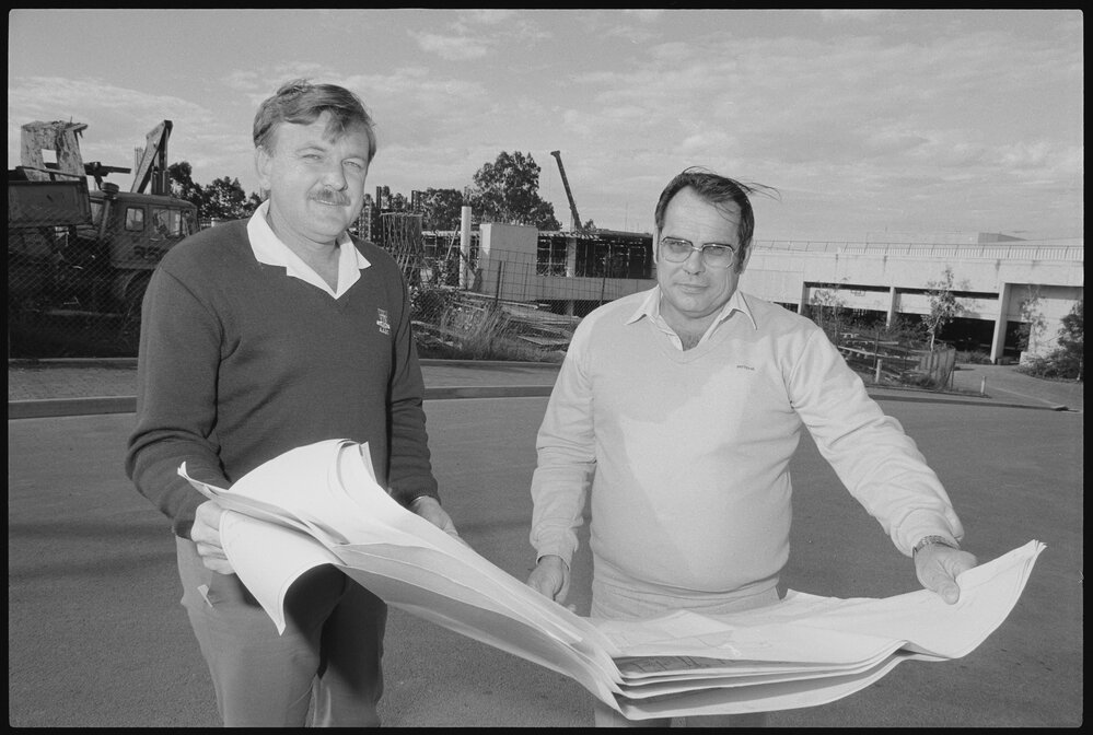 Unidentified people outside of a development perusing plans, Ipswich, August 1985