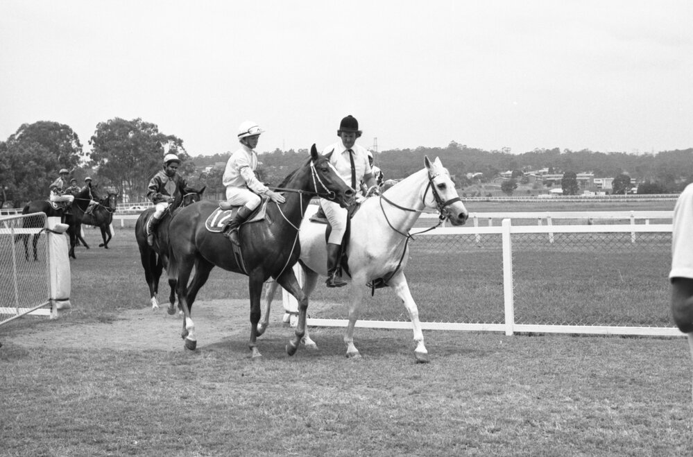 Ipswich Turf Club track official Ron Corvi and unidentified jockey riding horses at Ipswich Turf Club, Bundamba, Ipswich, Queensland, January 1978