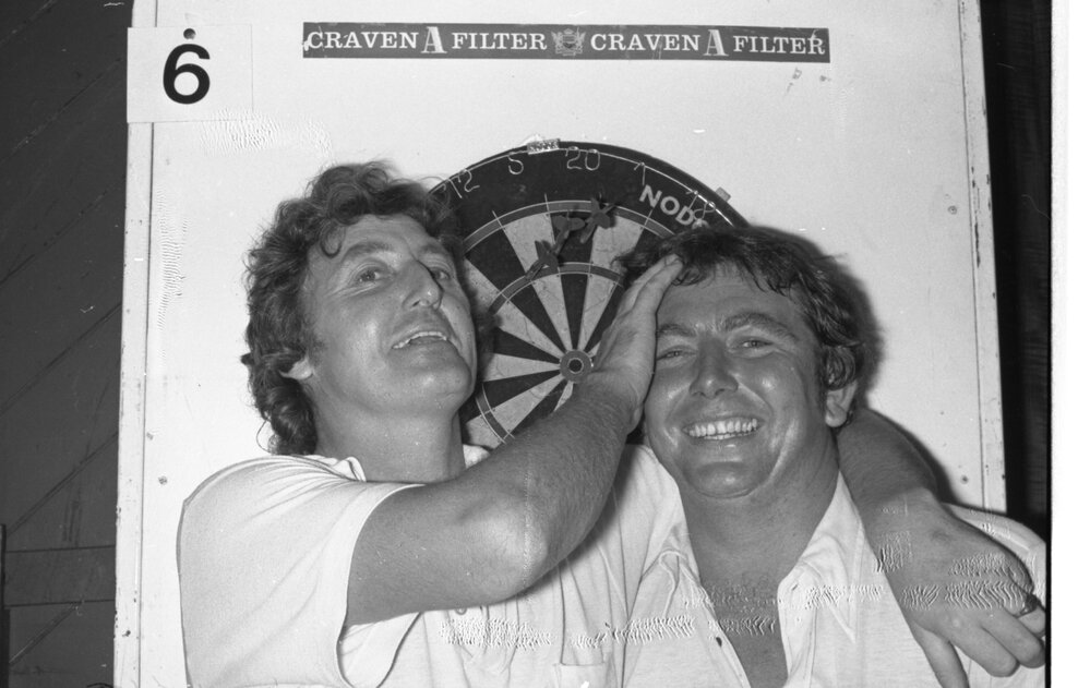 Two men with darts board, Ipswich, January 1978